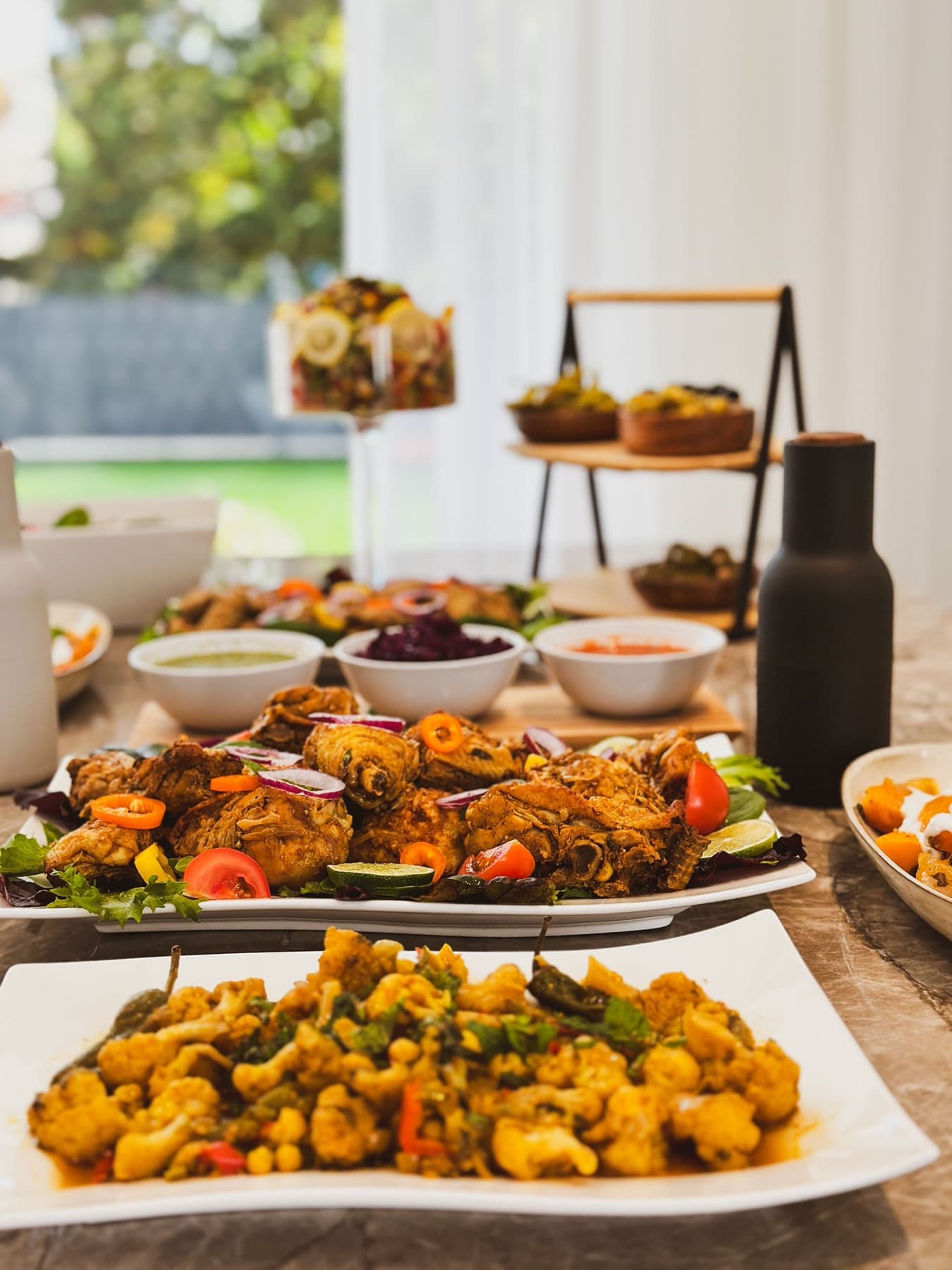 Aloo gobi, chicken pakoras and chutneys laid out on a table